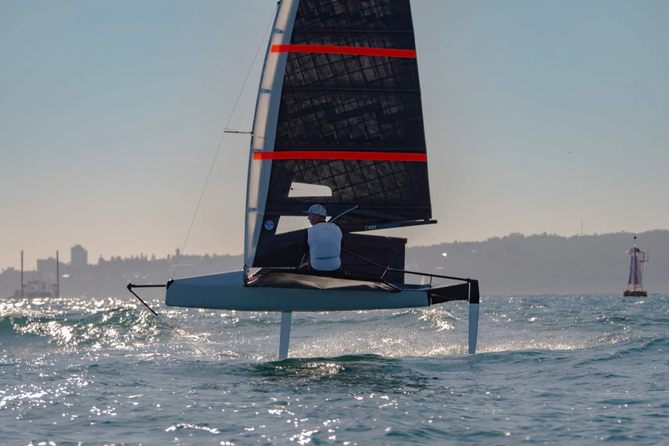 A foiling Moth sailboat flying above the water on hydrofoils during competitive racing